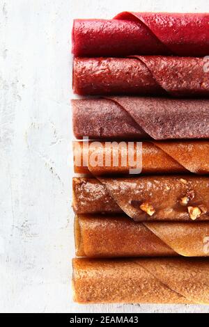 Die Pastille im Sortiment wird in Form eines Rohres aufgerollt. Gesundes Dessert auf hellem Hintergrund. Verschiedene Arten von getrockneten Früchten und Beerensäfte. Naturprodukt ohne Zucker. Draufsicht. Stockfoto