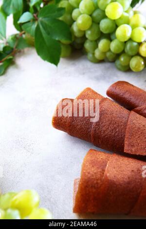 Natürliche leichte Traube Marshmallow wird in einem Rohr gerollt. Naturprodukt ohne Konservierungsstoffe. Essen für Vegetarier. Foto auf einem hellen Hintergrund. Blick von oben. Stockfoto