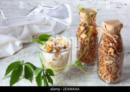 Müsli mit Joghurt in klarem Glas auf hellem Hintergrund. Granola in einer Glasflasche. Gesunde kalorienarme Lebensmittel. Naturprodukt. Vegetarisches Essen. Stockfoto