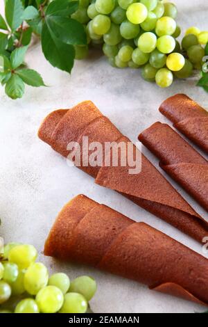 Natürliche leichte Traube Marshmallow wird in einem Rohr gerollt. Natürliches Bioprodukt ohne Konservierungsstoffe. Essen für Vegetarier. Foto auf einem hellen Hintergrund. Blick von oben. Stockfoto