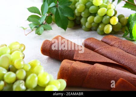 Natürliche Pastille aus leichten Trauben wird in ein Rohr gerollt. Naturprodukt ohne Konservierungsstoffe. Essen für Vegetarier. Stockfoto