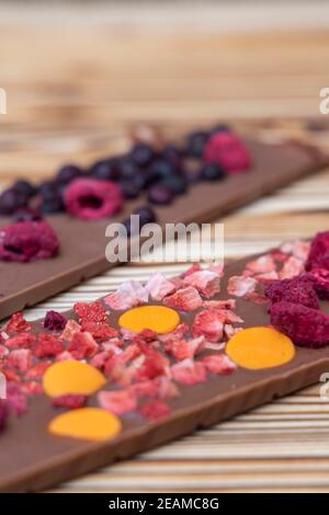 Verschiedene Arten von Schokolade mit getrockneten Früchten auf einem Holzbrett Stockfoto