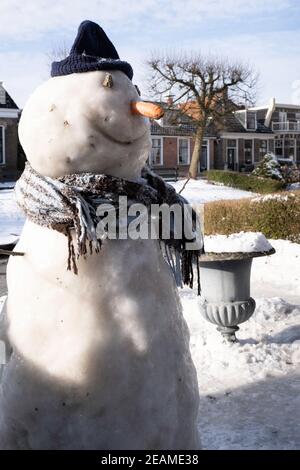 Schneemann in einem Garten in der Stadt IJlst in Friesland, Niederlande mit blauem Himmel und Sonne Stockfoto