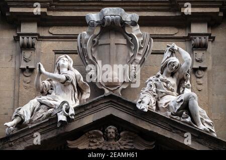 Statuen der Hoffnung und der Armut sitzen auf beiden Seiten der Arme des Theatine-Ordens über der zentralen Tür an der Fassade der Kirche Santi Michele e Gaetano in Florenz, Italien Stockfoto