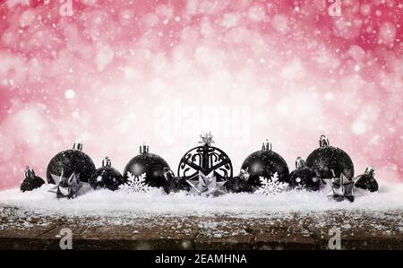 Red Christmas Background - dekoriert Black Balls on Snow mit Schneeflocken und Sternen auf Holzschreibtisch. Stockfoto