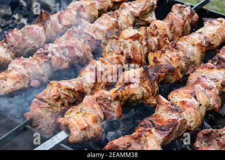 Braten Schwein am Spieß über einen brazier. Drehen Fleisch über Kohlen. Appetitlich Shish Kebab. Stockfoto