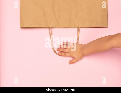 Kid Hand hält Papiertasche auf kreative Textur Stockfoto