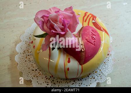 Moderne mehrschichtige Mousse Kuchen mit Spiegel mit Glasur bedeckt Essbare Zuckerrose und Schokoladenherz Stockfoto