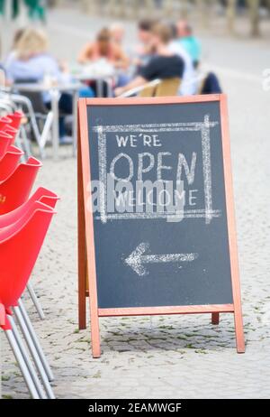 Willkommen offenes Schild, Restaurant oder Cafe bereit zum Service nach Corona Lockdown, Essen und Trinken Konzept, Plakatwand, Sandwich-Board in einem Café draußen Stockfoto