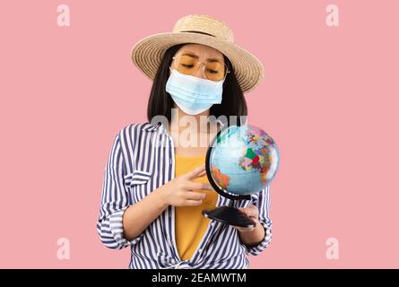 Traurige Asiatische Frau Hält Globe, Trägt Schützende Gesichtsmaske Stockfoto