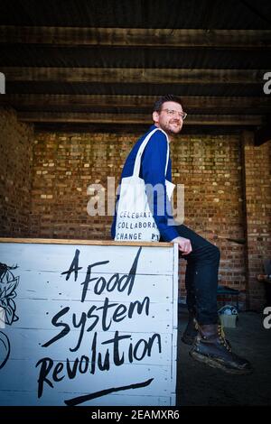 Mann sitzt am Tisch mit dem Slogan eine Revolution des Ernährungssystems . Stockfoto