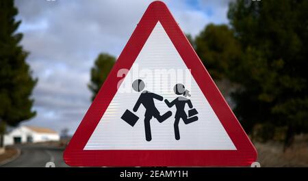 Detail eines dreieckigen Verkehrsschildes mit roter Grenze und weißem Hintergrund, der den Durchgang der Kinder zur Schule darstellt. Stockfoto