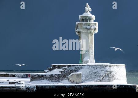 Sassnitz, Deutschland. Februar 2021, 10th. Der eisige Leuchtturm am Pier der Hafeneinfahrt. Frostiges Wetter und Schneefall behindern den Verkehr in Norddeutschland. Quelle: Jens Büttner/dpa-Zentralbild/dpa/Alamy Live News Stockfoto