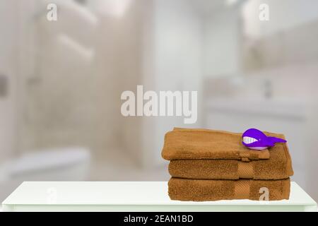 Tischplatte auf Handtücher Hintergrund. Nahaufnahme eines Stapels oder Stapels von braunen weichen Frottee-Badetüchern mit lustigen Walen darauf an einem hellen Tisch vor verschwommenem Badezimmerhintergrund. Platz. Stockfoto