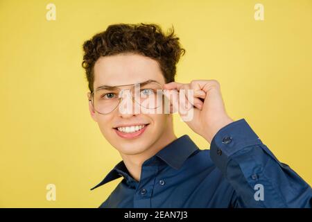 Lächelnd. Kaukasischen stattlichen Mann Porträt isoliert auf gelben Studio-Hintergrund mit Copyspace. Männliches Modell mit Brille. Konzept der menschlichen Emotionen, Gesichtsausdruck, Verkauf, Werbung, Mode. Stockfoto
