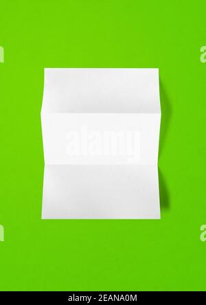 Blank gefaltet Weiß A4 Blatt Mockup-Vorlage auf grün Hintergrund Stockfoto