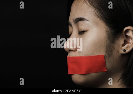 Asiatische Frau Augenbinde wickeln Mund mit rotem Klebeband Stockfoto