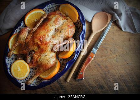 Ganze knusprige goldene gebratene Ente mit frischen Orangenscheiben für einen festlichen. Draufsicht rustikalen Holzhintergrund Stockfoto