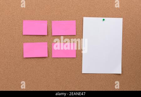 Leere rosafarbene und weiße, leere Papierstücke, die festgeklemmt sind Ein Korkbrett Stockfoto