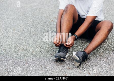 Sport Läufer schwarz Mann tragen Uhr sitzen er versuchen Schnürsenkel Laufschuhe Stockfoto