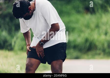 Sport Läufer schwarz Mann tragen Uhr Hände Gelenk halten Bein Beim Laufen hat sie Schmerzen in den Oberschenkeln Stockfoto