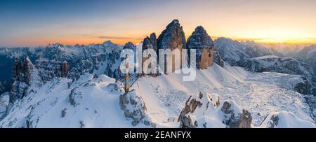 Gipfelkreuz auf schneebedeckter Monte Paterno mit Tre Cime Di Lavaredo im Hintergrund bei Sonnenuntergang, Sextner Dolomiten, Südtirol, Italien, Europa Stockfoto