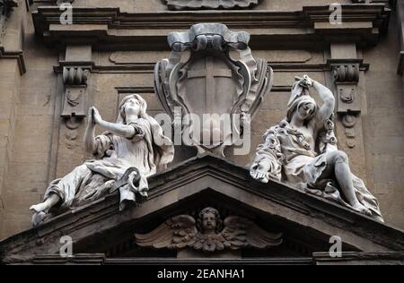 Statuen der Hoffnung und der Armut sitzen auf beiden Seiten der Arme des Theatine-Ordens über der zentralen Tür an der Fassade der Kirche Santi Michele e Gaetano in Florenz, Italien Stockfoto