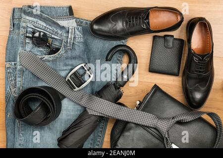 Klassische schwarze Schuhe und Herrenbekleidung und Accessoires liegen darauf Der Holzboden Stockfoto