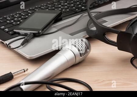 Laptop, Mikrofon, Kopfhörer liegen auf einem Holztisch Stockfoto