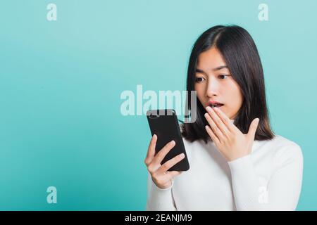 Frau überrascht schockiert mit Handy schließen Mund mit Handfläche Stockfoto