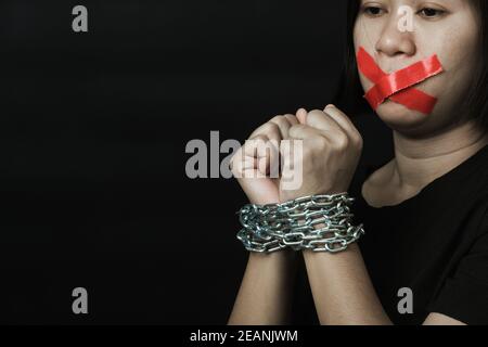 Asiatische Frau Augenbinde wickeln Mund mit rotem Klebeband und Sie war von Hand gebunden Stockfoto