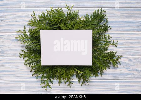 Mockup Weihnachtsgrusskarte und Tannenzweige auf blauem Holzhintergrund. Stockfoto