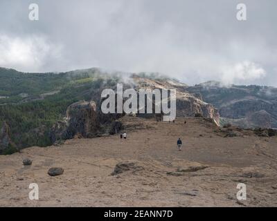 Blick vom Roque Nublo Plateau im Landesinneren der zentralen Berge vom berühmten Gran Canaria Wanderweg. Gruppe von touristischen Wanderern und Pinienwald in Stockfoto