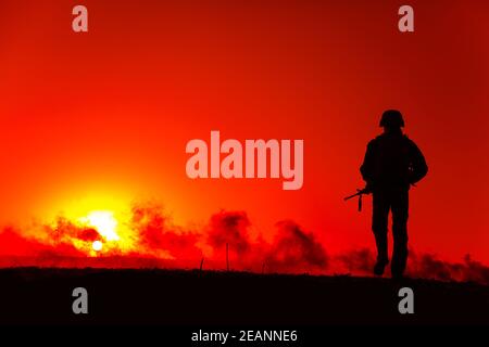 Armeesoldat, der bei Sonnenuntergang auf dem Schlachtfeld unterwegs ist Stockfoto