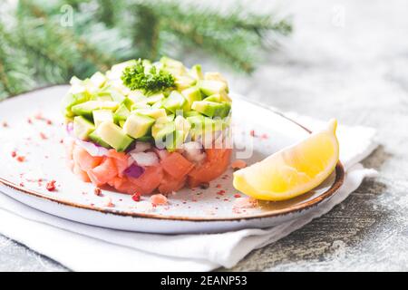 Salat aus rohem Lachs, Avocado und violetten Zwiebeln. Lachs-Tatar. Vorspeise für Silvester oder Weihnachtstisch Stockfoto