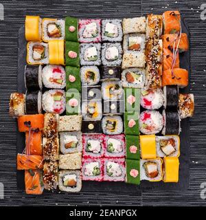 Japanisches Sushi-Essen. Maki und Brötchen mit Thunfisch, Lachs, Garnelen, Krabben und Avocado. Draufsicht auf verschiedene Sushi. Stockfoto