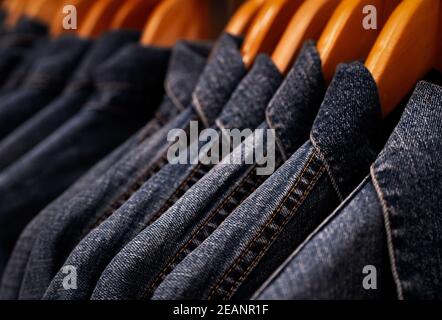 Selektiver Fokus auf Jacke Jeans hängen auf Rack im Bekleidungsgeschäft. Jeans mit Jeans-Muster. Textilindustrie. Jeans Mode und Shopping Konzept. Bekleidungskonzept. Jeansjacke auf Rack zum Verkauf. Stockfoto