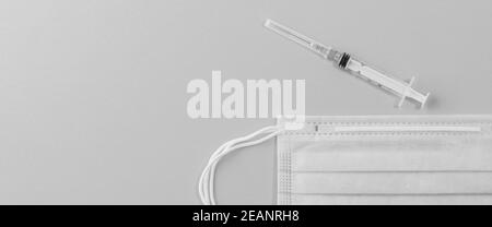 Medizinische Maske chirurgische Schutzvirus, Grippe, Krankheit, Pillen und Spritze. Isoliert auf einem rosa Hintergrund. Stockfoto