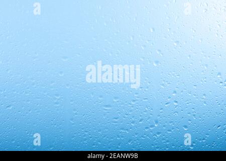 Regentropfen auf Glasfenster über grauem und blauem Himmel Stockfoto