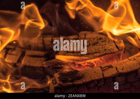 Ein loderndes Feuer im Dunkeln. Entzündung des Brennholzes im Feuer. Ein helles brennendes Feuer. Funken und Flammen in der Dunkelheit. Rot-heiße Hitze und Zungenflammen.Feurig flammendes Lagerfeuer. Stockfoto