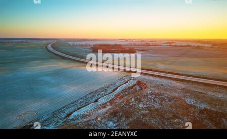 Winter grün Agrarfeld Winterpflanzen unter Schnee-Panorama. Highway Dezember Sonnenuntergang Luftaufnahme. Stockfoto