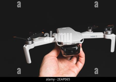 Kiew, Ukraine - 02. Februar 2021: DJI Mavic Mini 2 Drohne Nahaufnahme. Hand hält ausgeklappten Quadcopter auf schwarzem Hintergrund Stockfoto