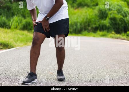 Sport Läufer schwarz Mann tragen Uhr Hände Gelenk halten Bein Beim Laufen hat sie Schmerzen in den Oberschenkeln Stockfoto