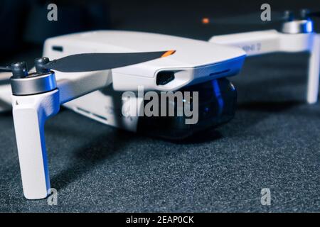 Kiew, Ukraine - 02. Februar 2021: DJI Mavic Mini 2 Drohne Nahaufnahme. Neue Quadcopter-Gadget auf schwarzem Hintergrund in blauem Licht Stockfoto