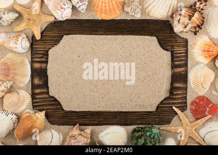 Holzrahmen auf dem Sand, Sterne, Muscheln und Steine um. Mit Platz für Design, Text Ort. Stockfoto