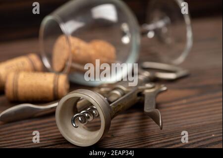 Korkenzieher und Korken aus Weinflaschen auf einem Holztisch. Nahaufnahme, selektiver Fokus. Stockfoto