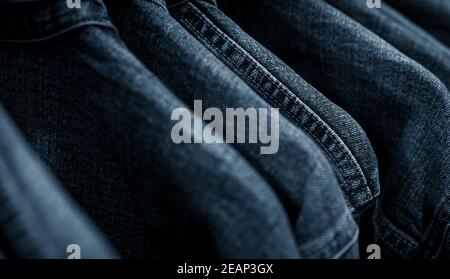 Selektiver Fokus auf Jacke Jeans hängen auf Rack im Bekleidungsgeschäft. Jeans mit Jeans-Muster. Textilindustrie. Jeans Mode und Shopping Konzept. Bekleidungskonzept. Jeansjacke auf Rack zum Verkauf. Stockfoto