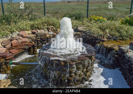 Kleiner Brunnen im Blumenbeet Bereich Stockfoto
