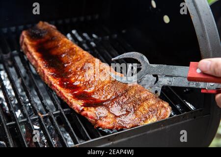 Nahaufnahme von BBQ Braten und geräuchertem Schweinefleisch Spareribs glasiert mit sauze auf dem Hot Charcoal Grill mit Flammen, Grill und Hobby-Konzept Stockfoto