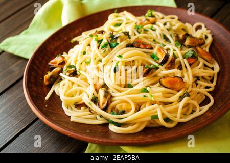 Italienische Spaghetti mit Garnelen und Muscheln auf braunem Teller Stockfoto